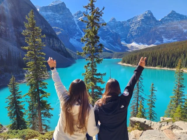 Two girls sitting at the Moraine Lake on Banff tour from Toronto. LGBT