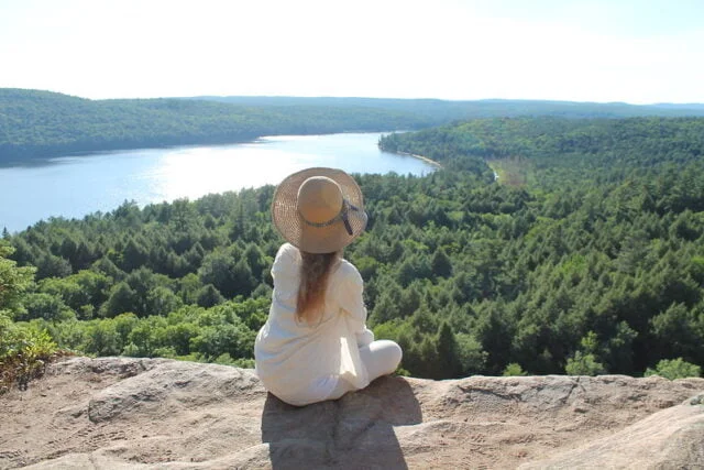 Girl sitting at Booth's rock lookout, looking at the lake