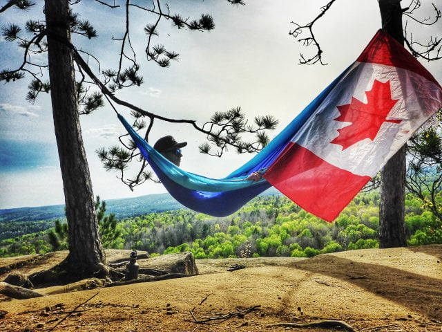 Guy lying in hammock with Canadian Flag on Algonquin park hiking tour. 